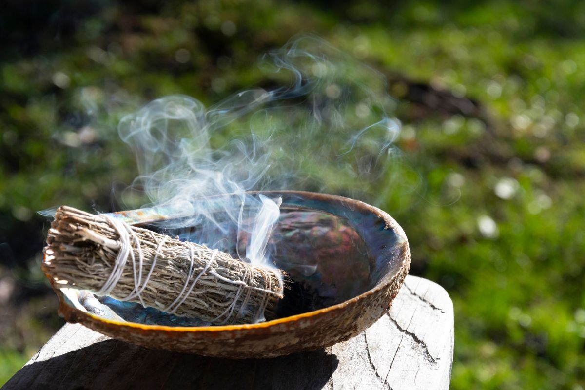 A smudge bowl with smouldering sage and sweetgrass