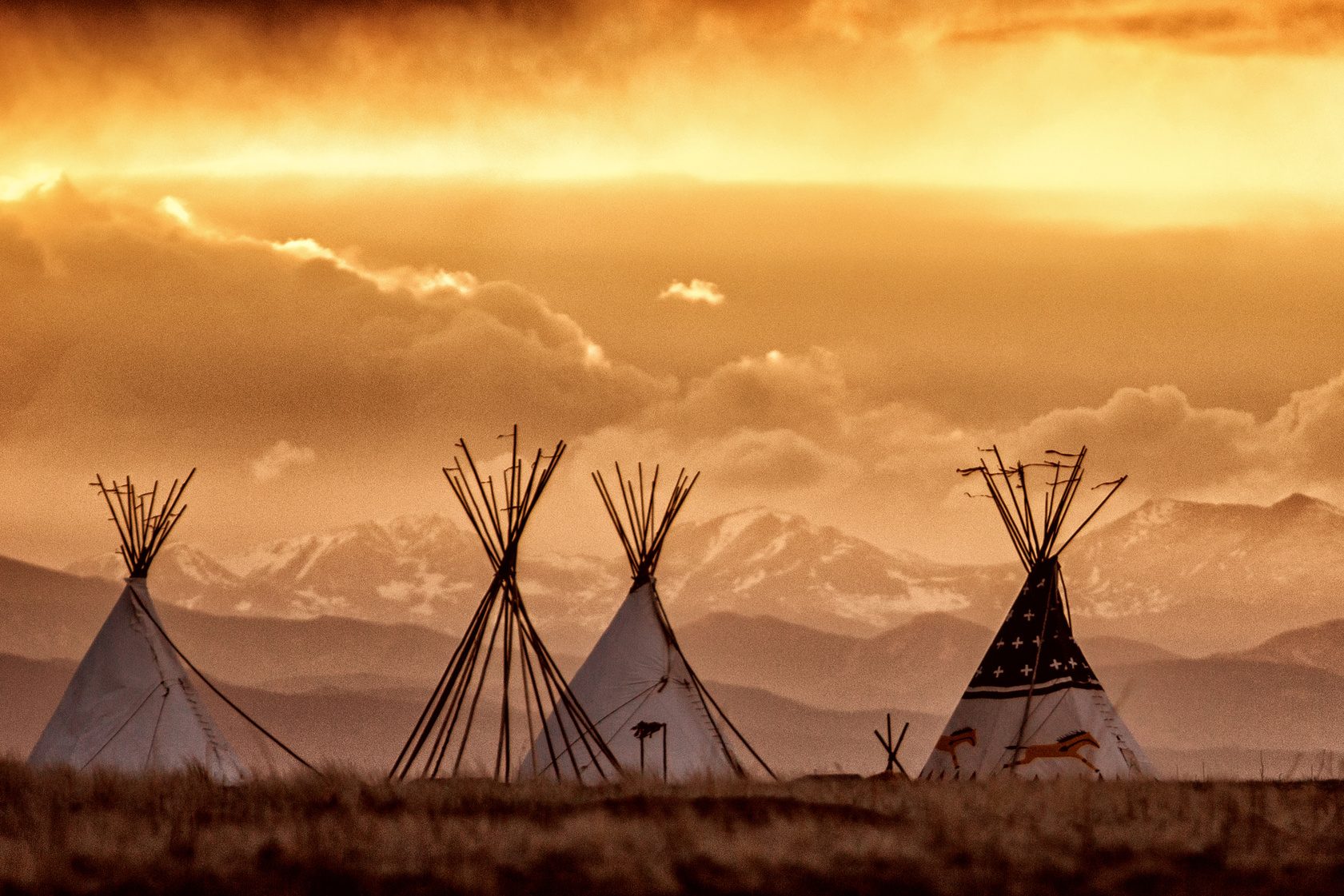 Tipis at sunset against the Rocky Mountains on the prairie. Ben Calf Robe Society, Our Children Are Sacred